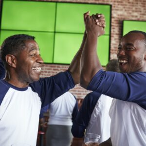 Male Friends Watching Game In Sports Bar Celebrating