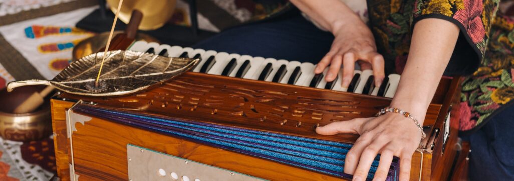 Hands of a woman sitting on the floor and playing the harmonium during the practice of kundalini