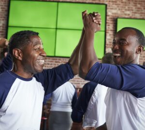 Male Friends Watching Game In Sports Bar Celebrating