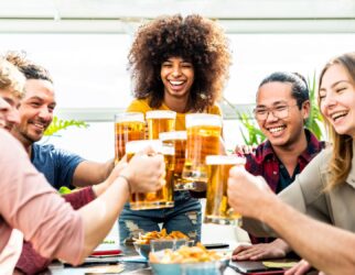 Mixed race group of friends toasting beer glasses at brewery pub